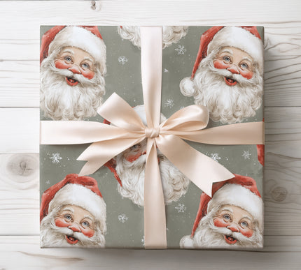 Nostalgic vintage Santa faces combined with snowflakes on a muted green backdrop, great for classic Christmas wrapping. 