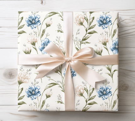 Wrap gifts in soft elegance with Petalwhisper Dusk paper, showcasing blue and cream blossoms on an ivory background. Ideal for weddings and refined occasions.